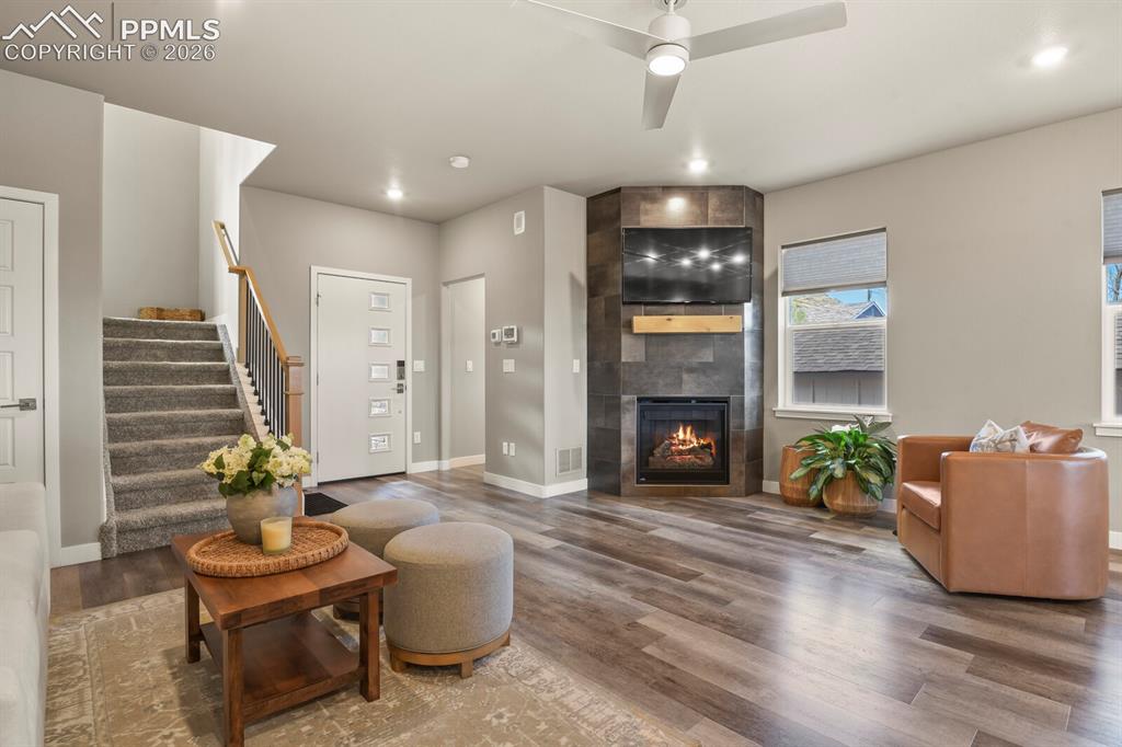 Image 9 of 33: Spacious living area featuring wood-finish flooring, a corner fireplace wit