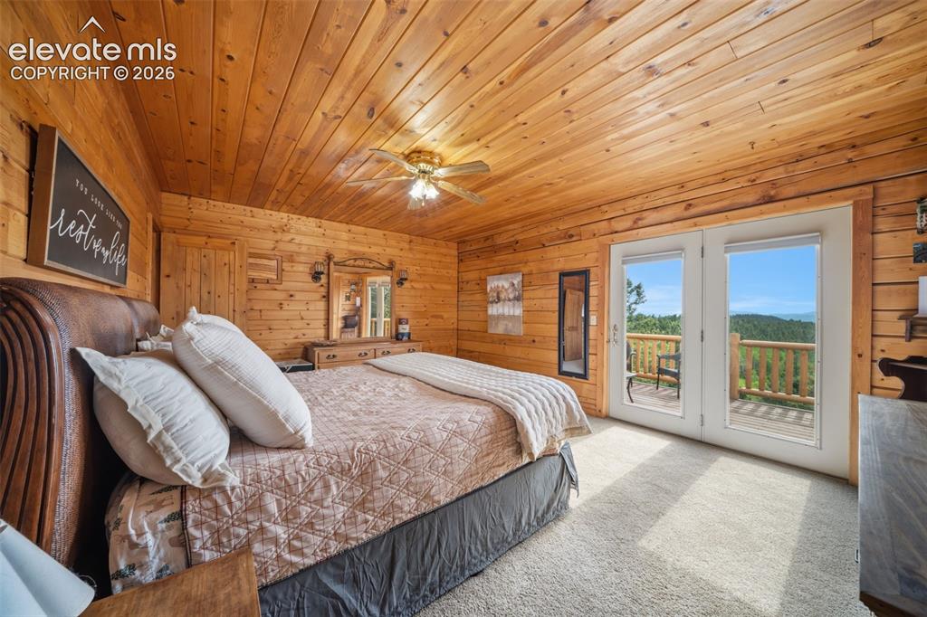 Image 11 of 39: Main level primary bedroom with walk out to back deck and the view are stun