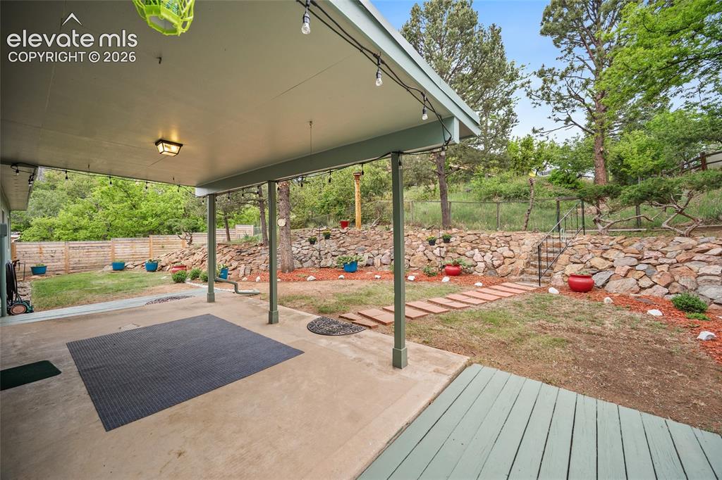 Image 12 of 50: Covered concrete patio with overhead lighting and string lights