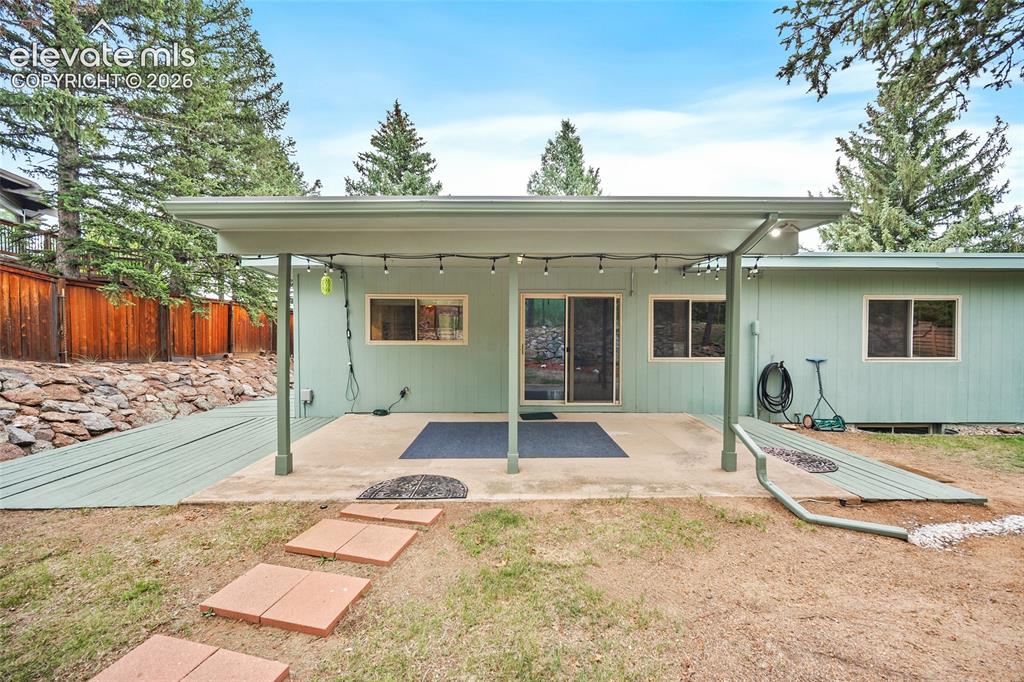 Image 13 of 50: Covered concrete patio with overhead lighting, featuring multiple windows a