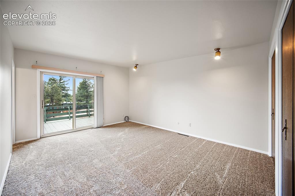 Image 16 of 50: Spacious room featuring light-colored walls and patterned carpeting