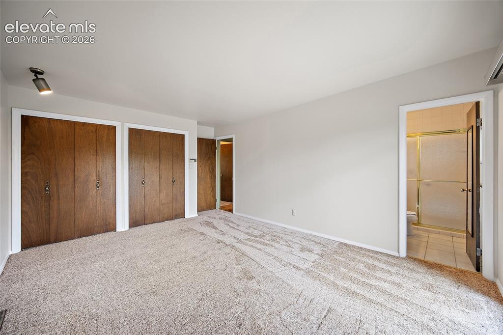 Image 19 of 50: Carpeted room featuring multiple wood-finish bi-fold closet doors, a ceilin