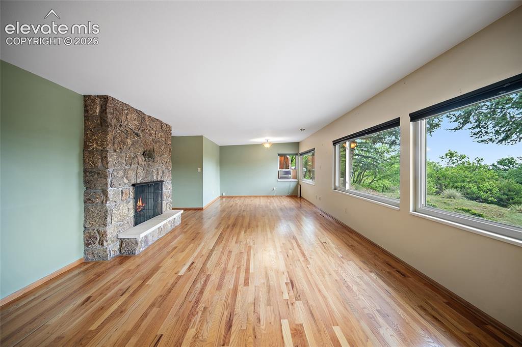 Image 2 of 50: Spacious interior featuring wood-finish flooring, a stone-clad fireplace wi