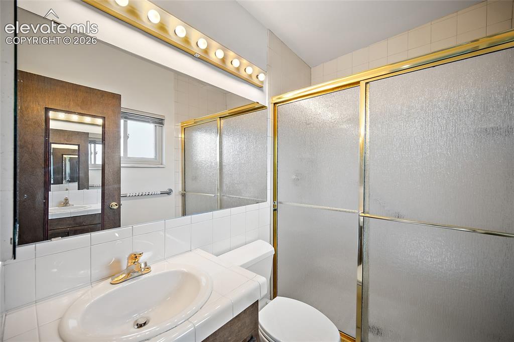 Image 20 of 50: Bathroom featuring a vanity with a drop-in sink, gold-tone faucet, and a la