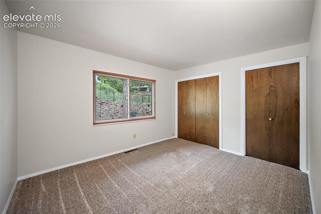 Image 21 of 50: Neutral tone wall paint with a window featuring wood trim, two sets of bi-f