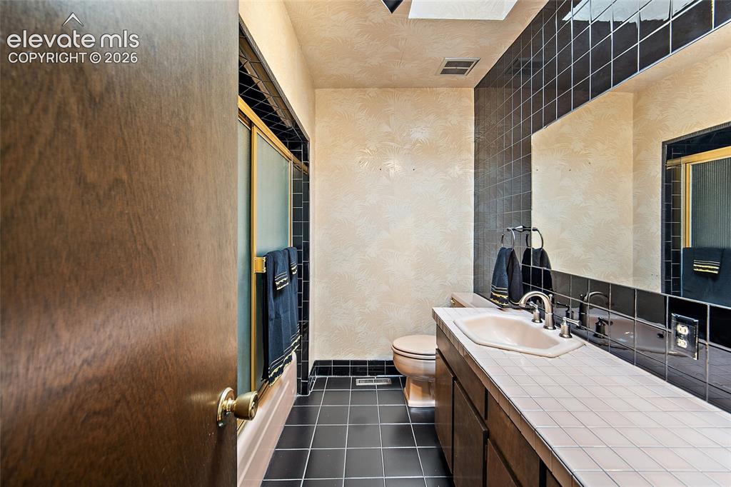 Image 23 of 50: Bathroom featuring a tiled vanity with a built-in sink, dark wood-finish ca