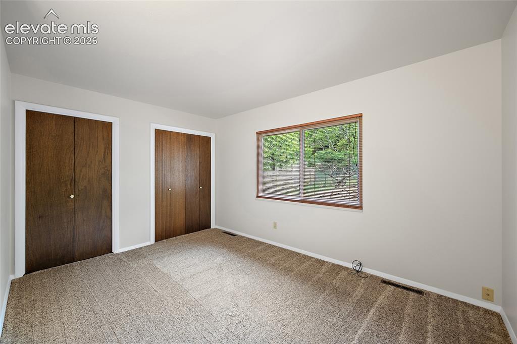 Image 24 of 50: Carpeted interior space featuring neutral wall tones, two bi-fold closet do