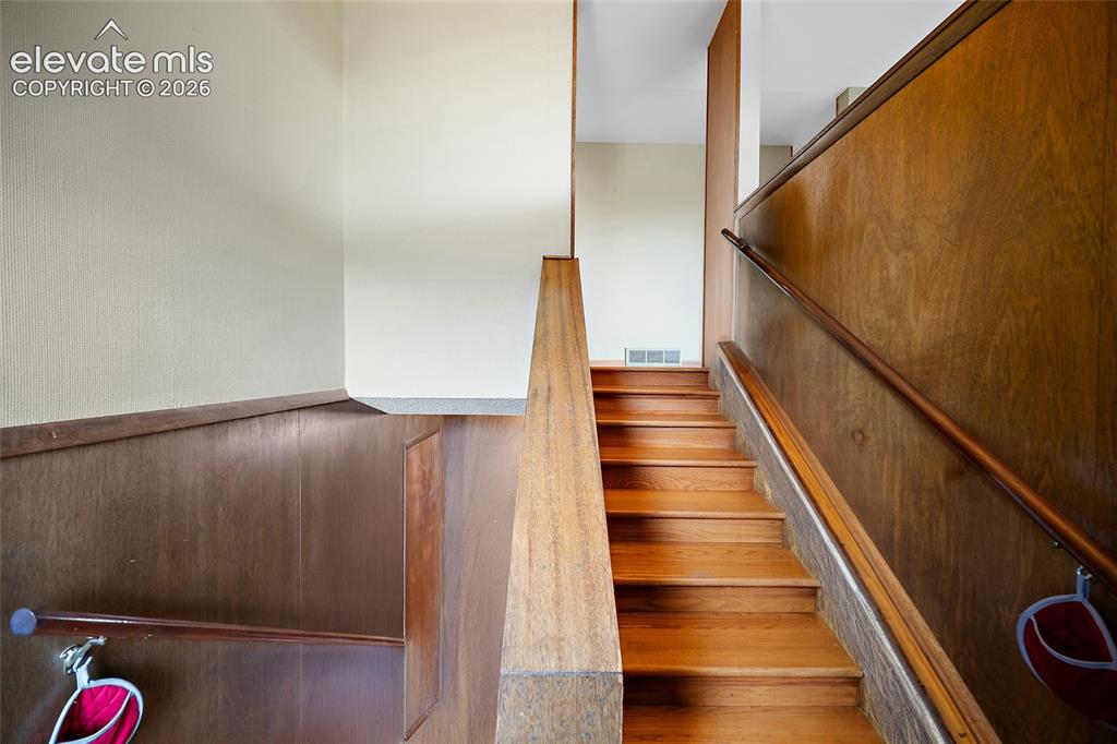 Image 25 of 50: Hardwood staircase featuring wood paneling and handrails