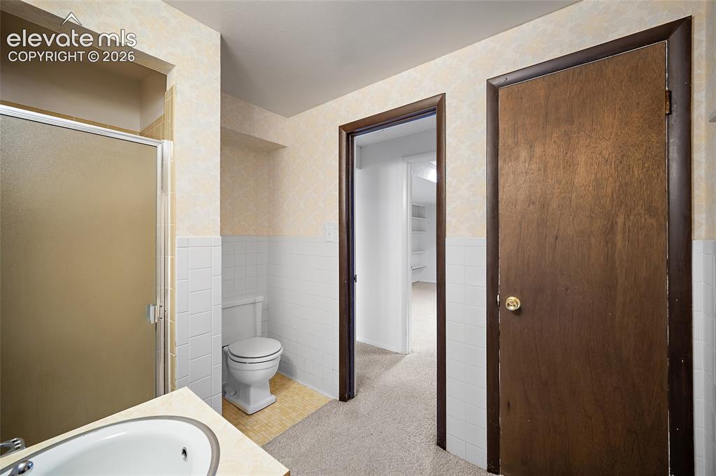 Image 31 of 50: Bathroom featuring a built-in shower with a frosted glass enclosure, white