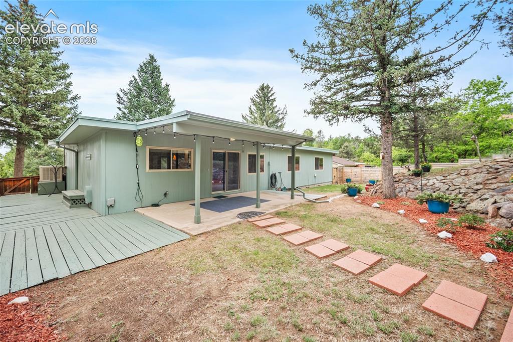 Image 34 of 50: Rear exterior featuring a covered patio, sliding glass doors, and a wood de