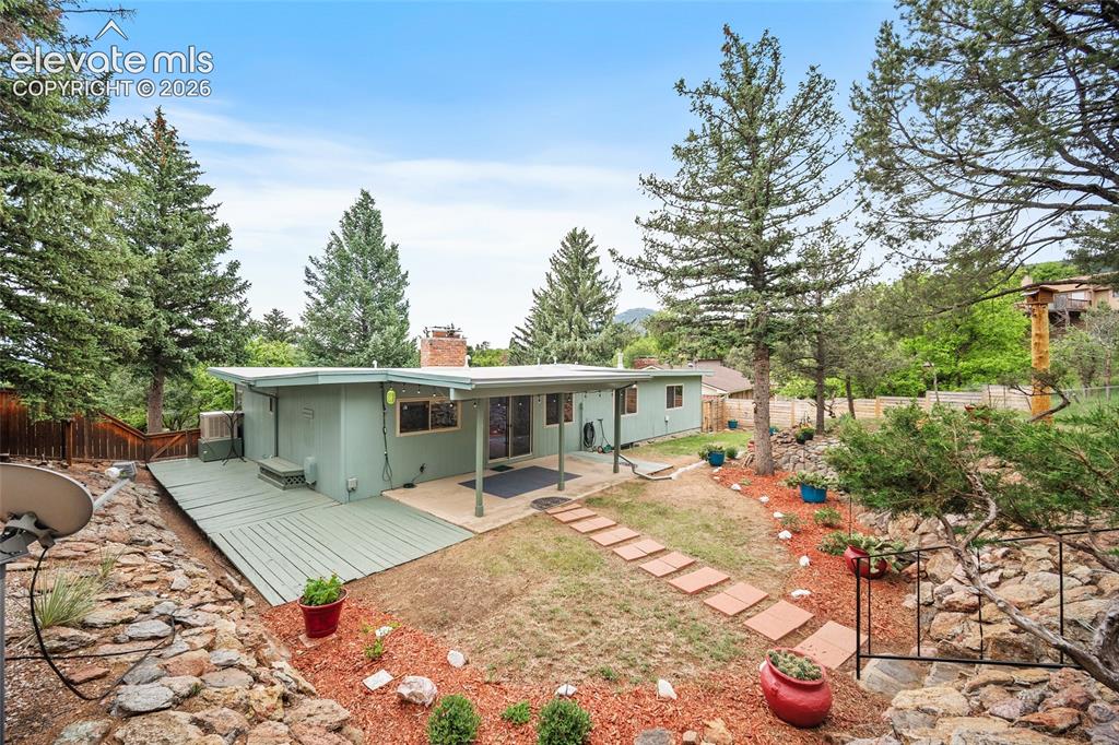 Image 35 of 50: Rear exterior featuring a multi-level deck, covered patio, and a stone path