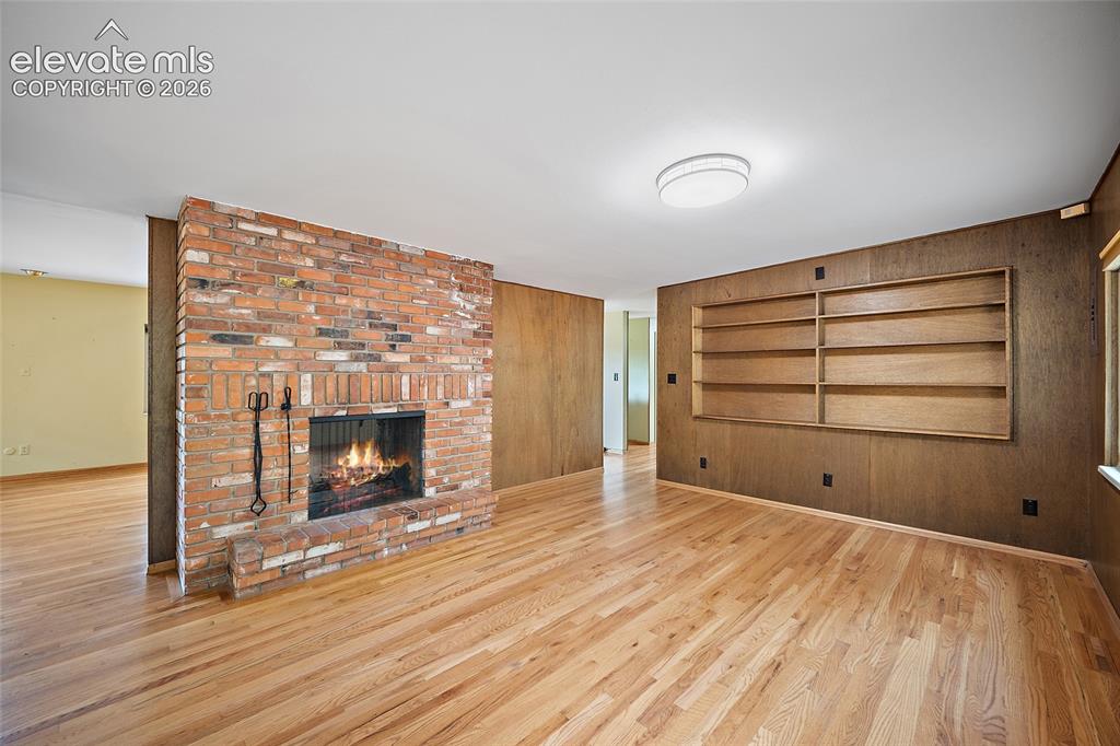 Image 4 of 50: Open concept living space featuring a brick fireplace, built-in shelving, w
