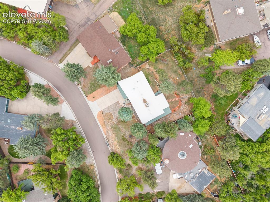 Image 41 of 50: Residential property on a curved street with mature trees and varied landsc