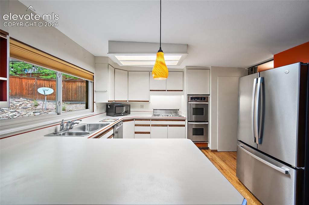Image 9 of 50: Kitchen featuring a large pass-through window with outdoor views, white cab