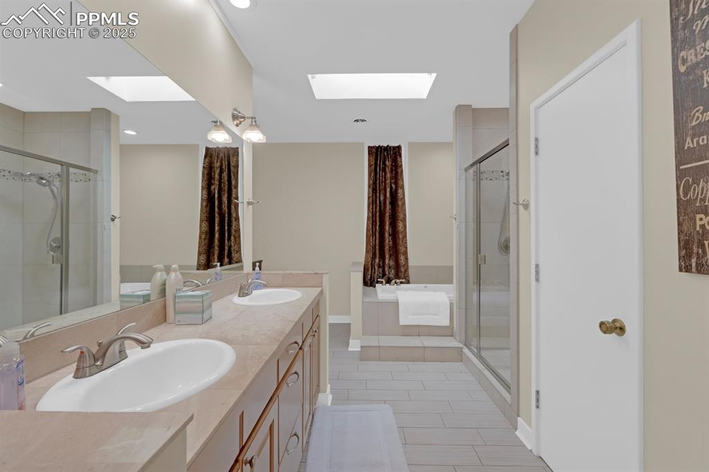 Image 26 of 43: 5 pc bath featuring a skylight and double vanity