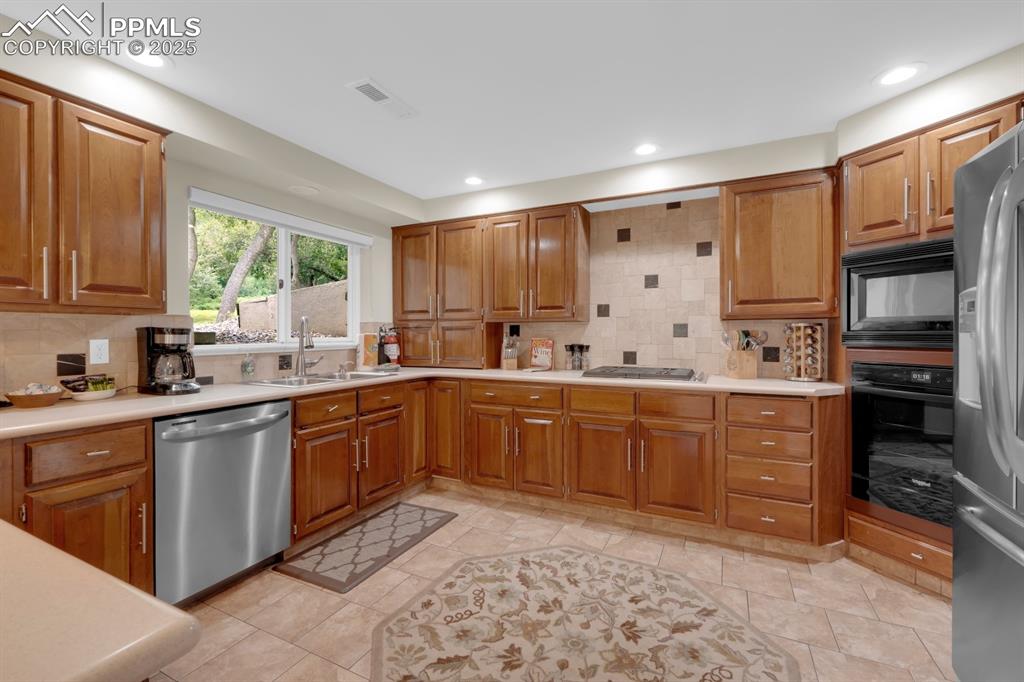 Image 5 of 43: Kitchen featuring tasteful backsplash, black and stainless appliances with 