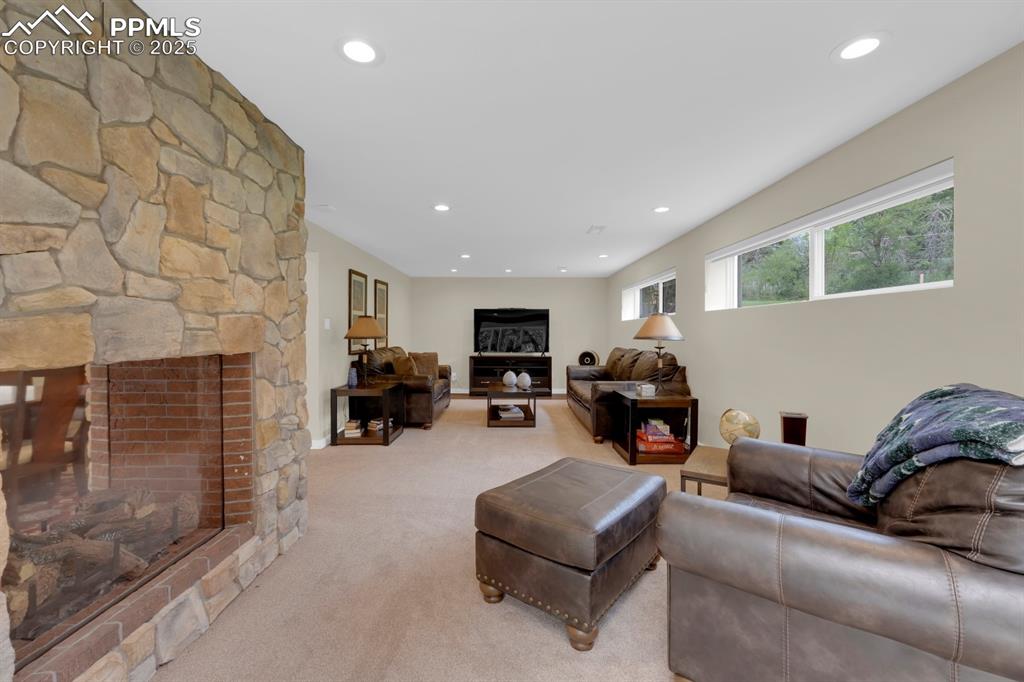 Image 9 of 43: Living room featuring a stone fireplace and recessed lighting