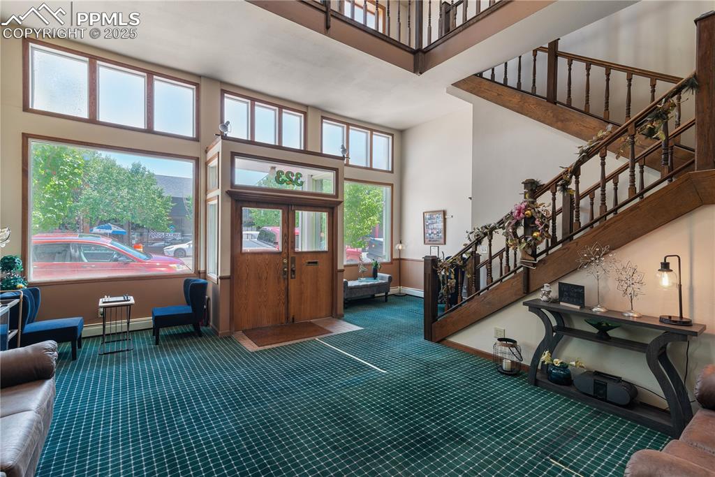 Image 12 of 31: Foyer entrance with a high ceiling, stairway, a baseboard radiator, and car