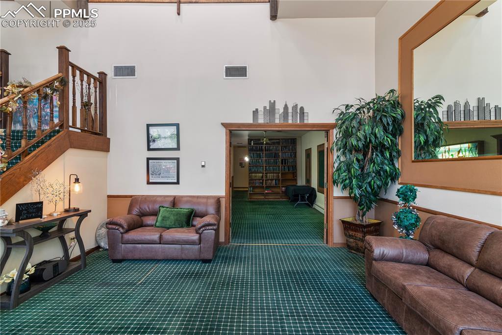 Image 14 of 31: Living area with carpet floors, stairway, and a towering ceiling