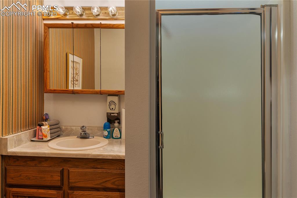 Image 24 of 31: Full bath featuring vanity, a shower stall, and wallpapered walls