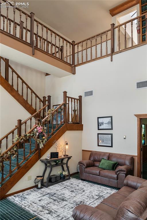 Image 7 of 31: Living room with a high ceiling, carpet, and stairway