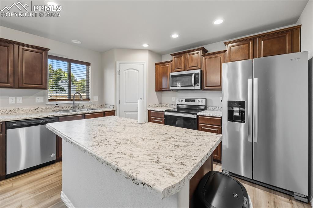 Image 11 of 33: Kitchen with appliances with stainless steel finishes, light countertops, l