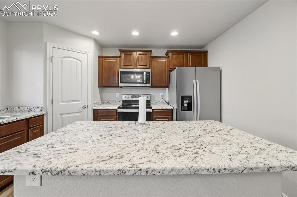 Image 12 of 33: Kitchen featuring stainless steel appliances, light stone countertops, a ce