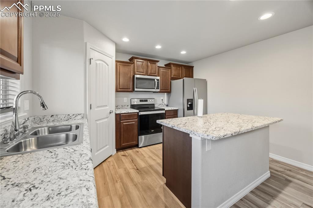 Image 13 of 33: Kitchen with appliances with stainless steel finishes, a center island, rec