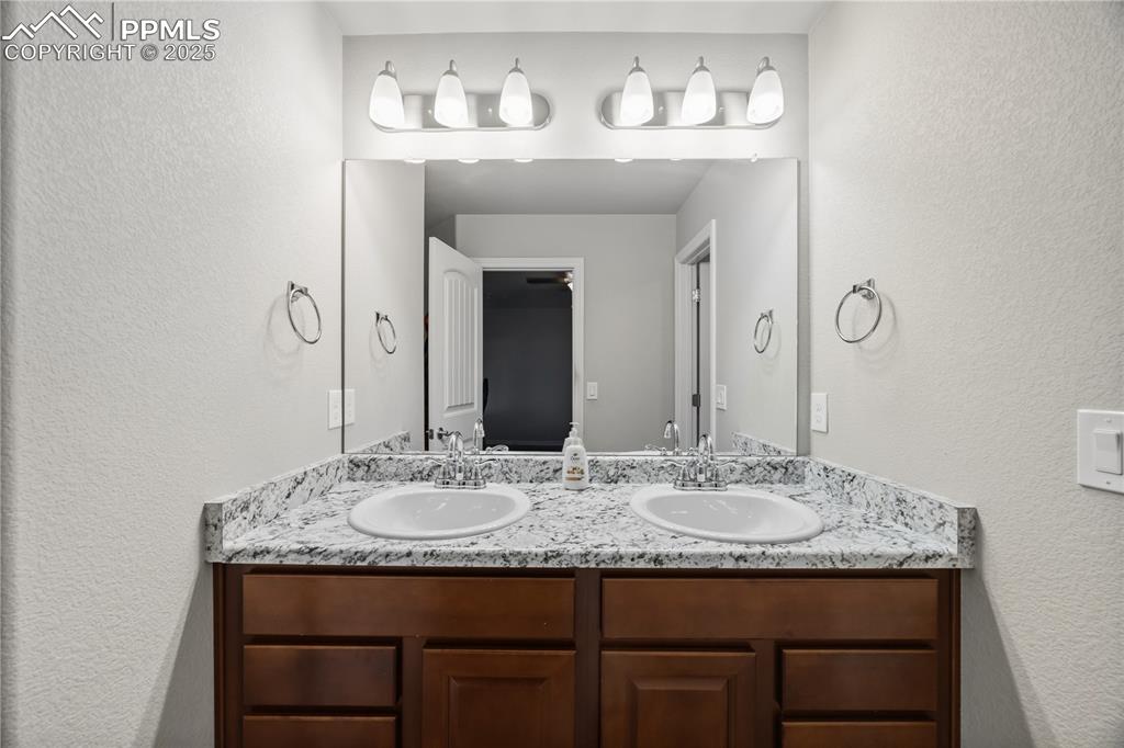 Image 19 of 33: Bathroom with a textured wall and double vanity