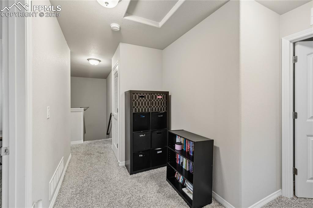 Image 30 of 33: Hallway with light carpet and an upstairs landing
