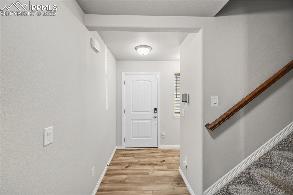 Image 4 of 33: Entrance foyer with light wood-style flooring, a textured wall, and stairs