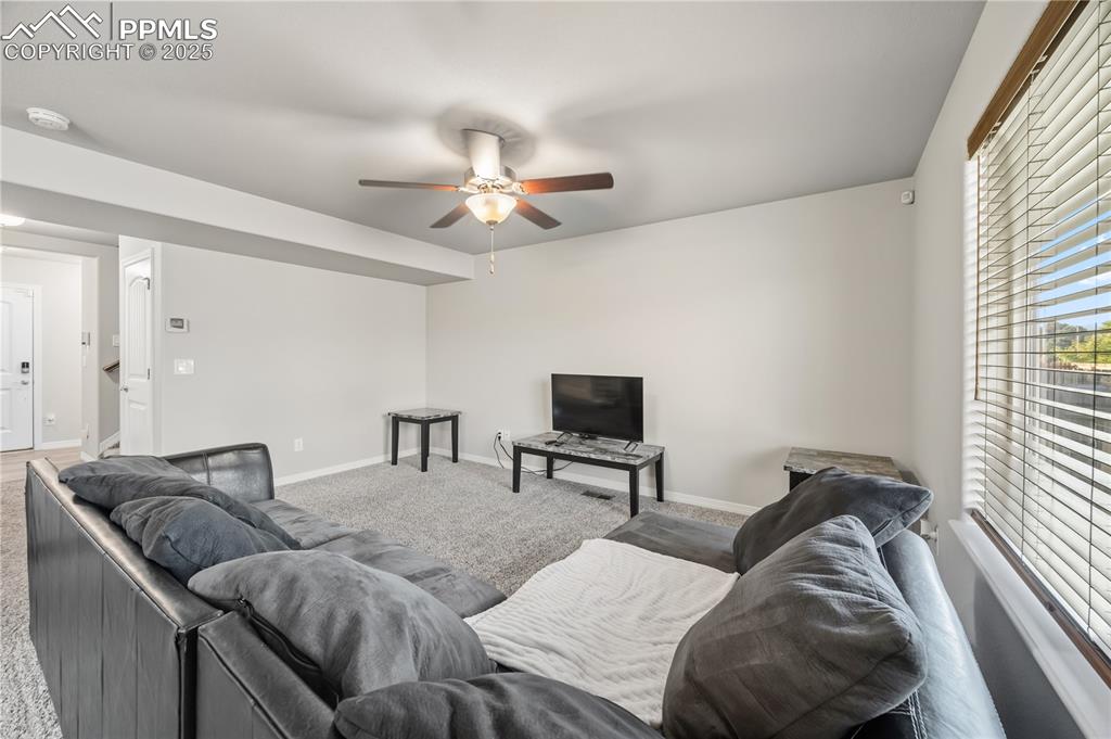 Image 8 of 33: Living area featuring carpet and ceiling fan