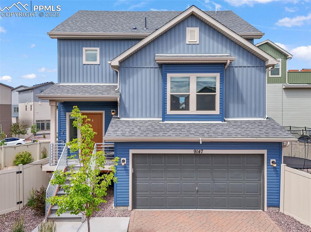 Caption: View of front of property featuring a garage, a shingled roof, board and batten siding, and decorati
