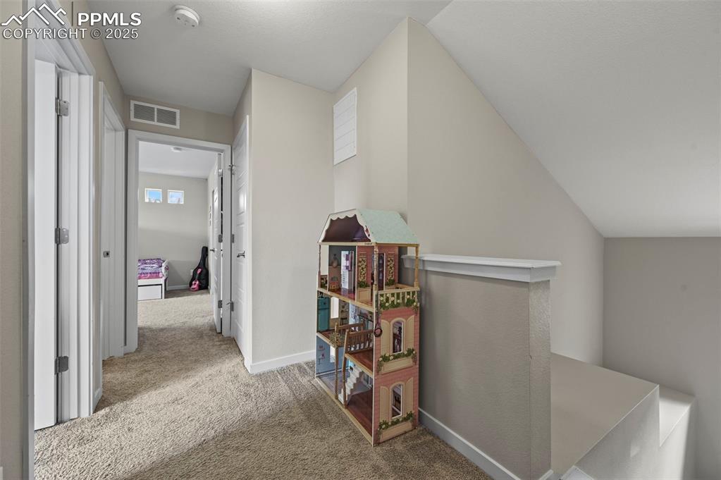Image 19 of 44: Hallway with carpet floors and an upstairs landing