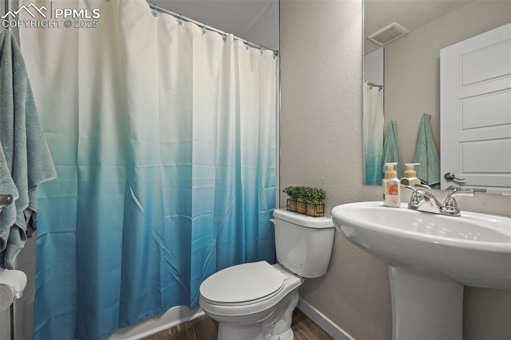 Image 32 of 44: Full bathroom featuring wood finished floors, a shower with curtain, and a 