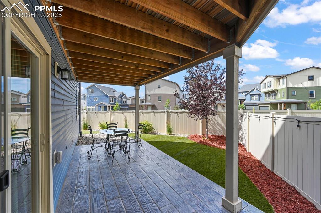 Image 34 of 44: Fenced backyard with a residential view, outdoor dining space, and a deck