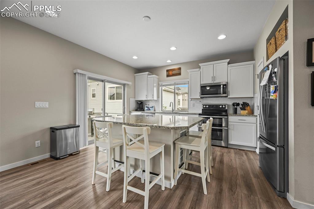 Image 7 of 44: Kitchen with appliances with stainless steel finishes, dark wood-type floor