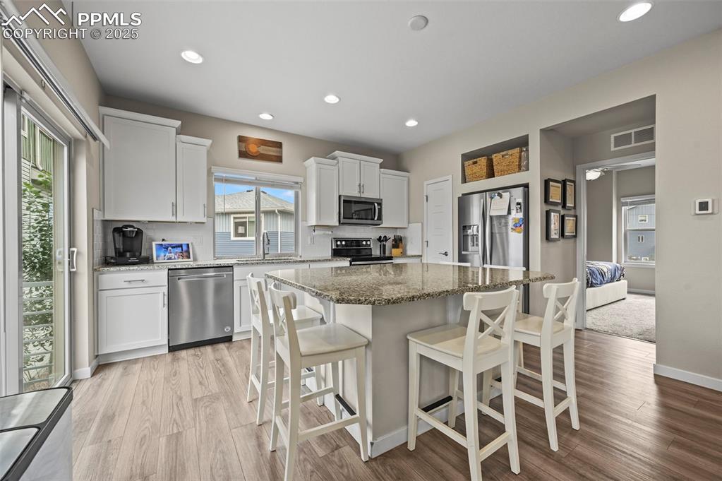 Image 8 of 44: Kitchen featuring stainless steel appliances, light wood-style flooring, ta