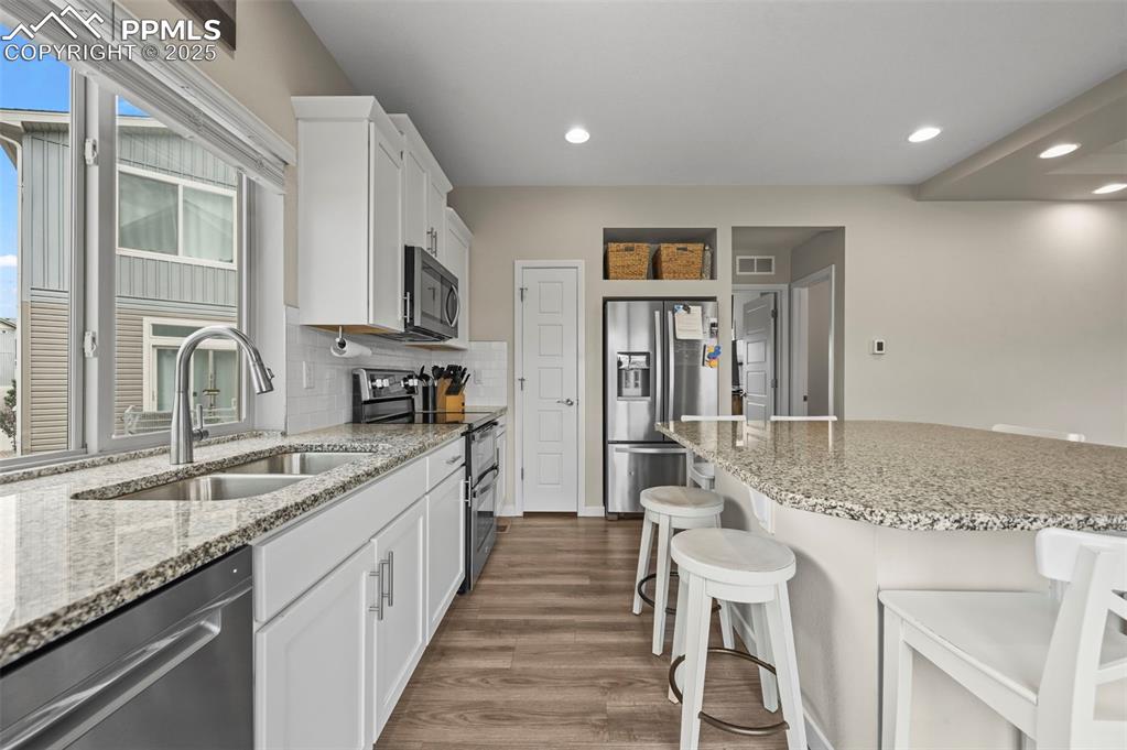Image 9 of 44: Kitchen featuring stainless steel appliances, a kitchen bar, dark wood fini