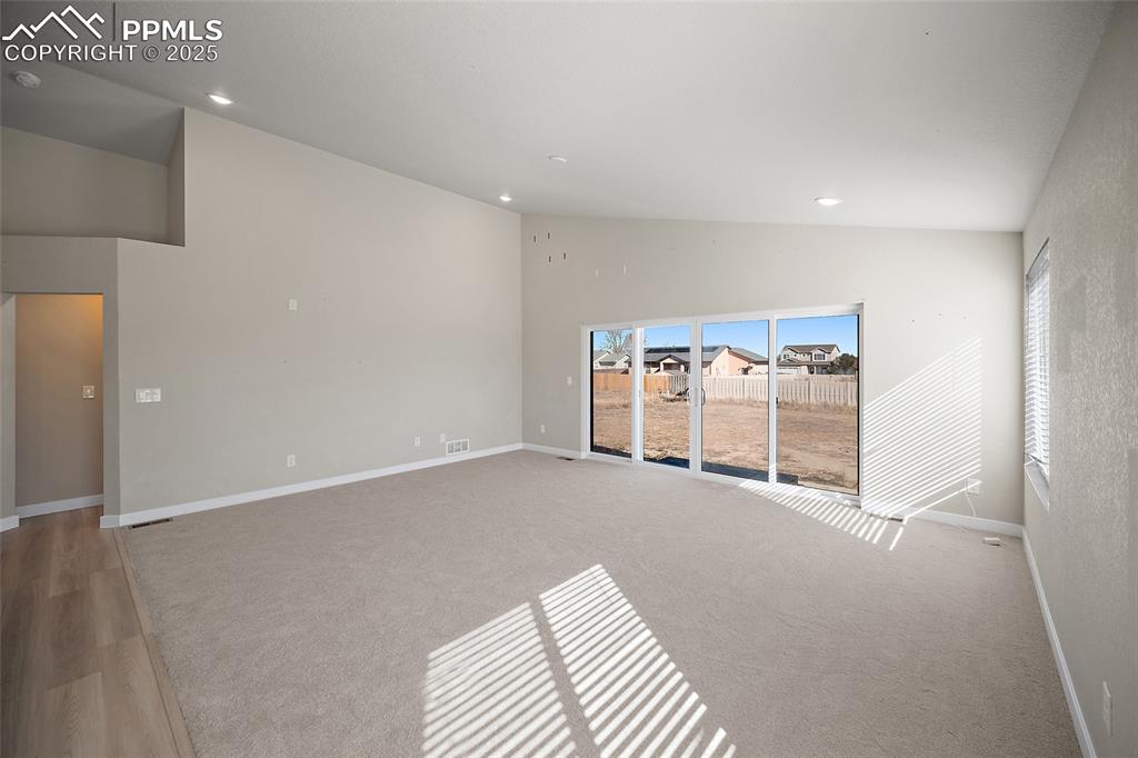 Image 11 of 30: Empty room featuring recessed lighting, light colored carpet, and high vaul