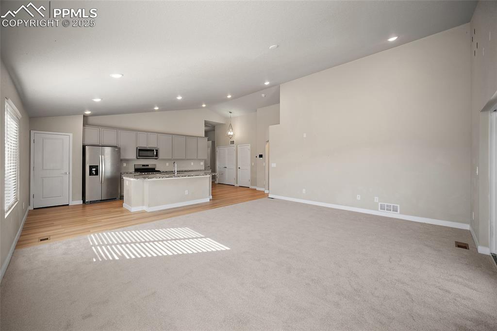 Image 12 of 30: Kitchen featuring lofted ceiling, stainless steel appliances, open floor pl