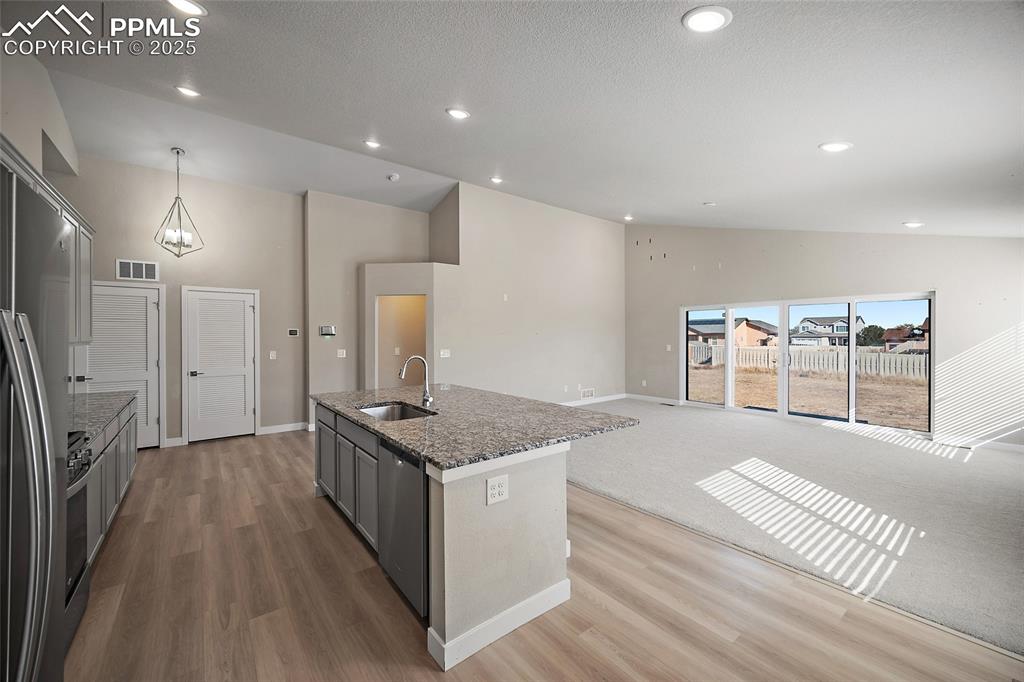 Image 15 of 30: Kitchen with gray cabinetry, recessed lighting, dark stone counters, applia