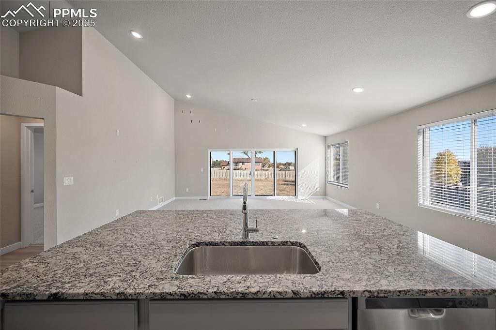 Image 18 of 30: Kitchen with light stone countertops, recessed lighting, stainless steel di
