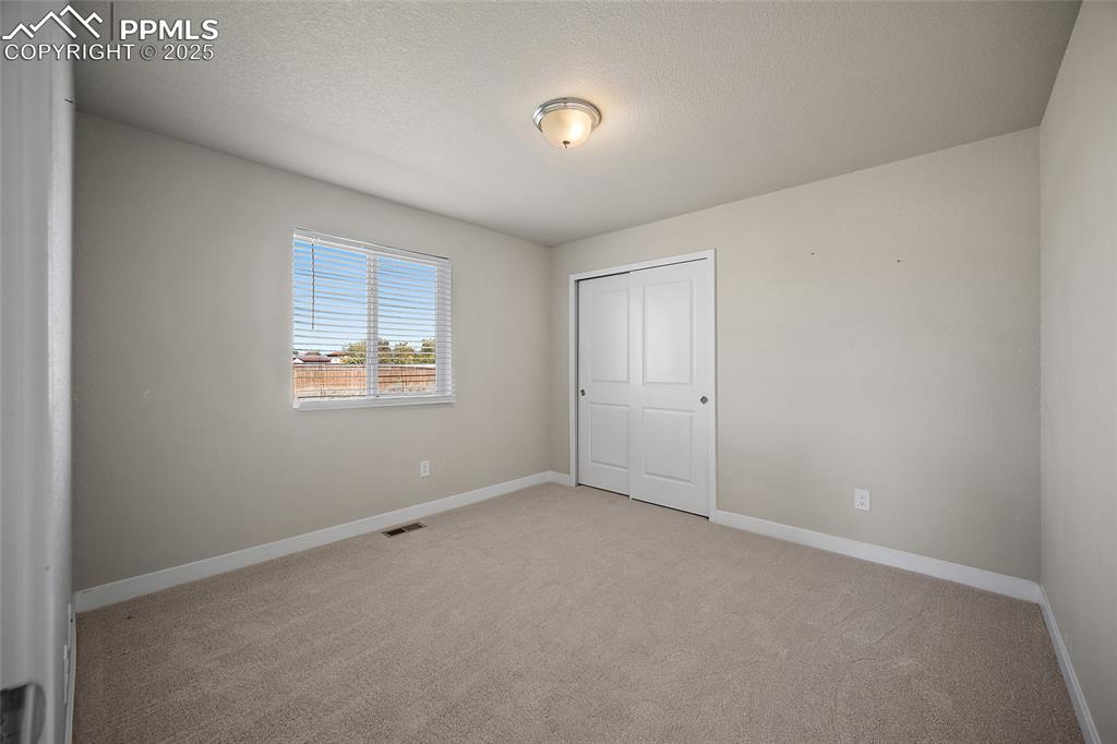 Image 20 of 30: Unfurnished bedroom with light carpet, a textured ceiling, and a closet