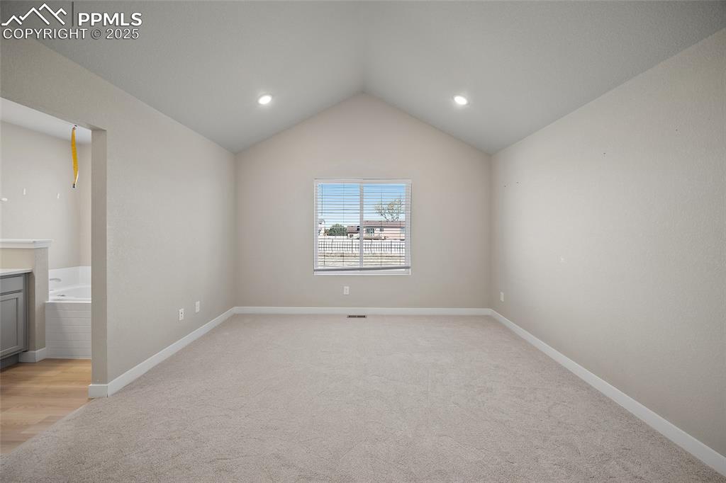 Image 25 of 30: Spare room with vaulted ceiling, light carpet, and recessed lighting