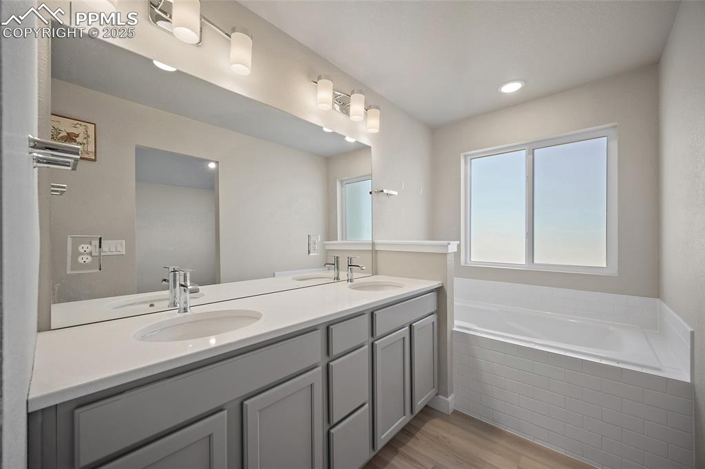 Image 4 of 30: Bathroom featuring double vanity, a bath, light wood-type flooring, and rec