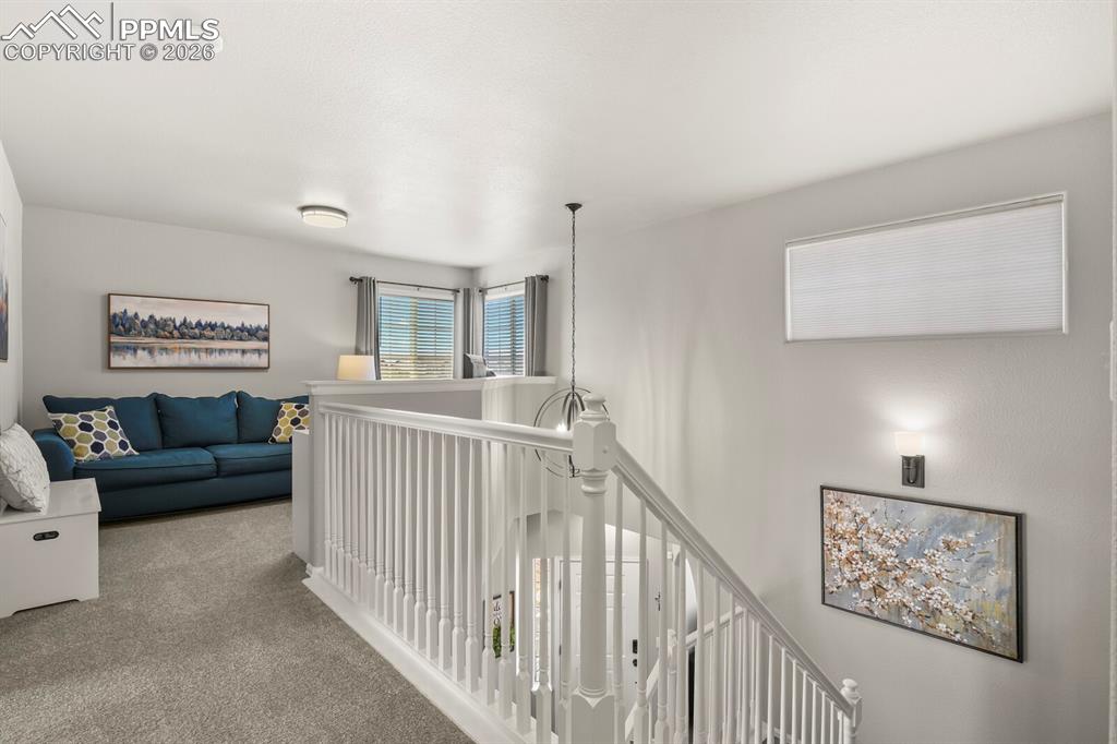 Image 26 of 40: Hall featuring an upstairs landing and carpet