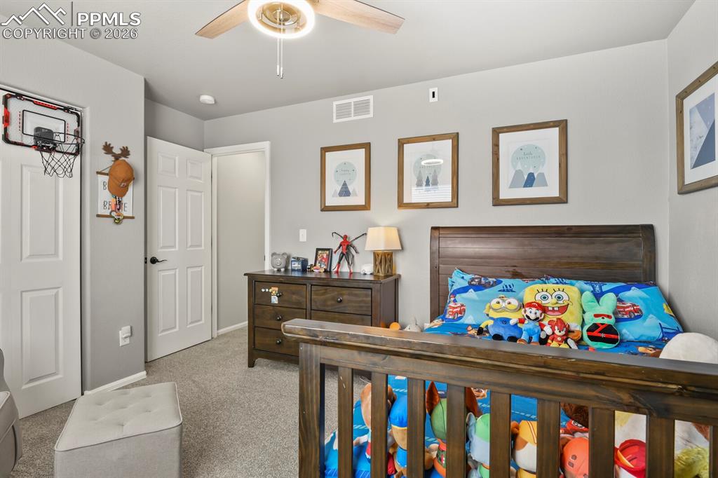 Image 33 of 40: Bedroom with a ceiling fan and light carpet