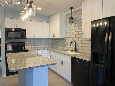 Image 3 of 28: Beautiful glass tiled backsplash.  Room for a full-sized fridge.
