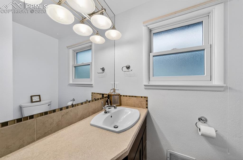 Image 29 of 46: Bathroom featuring a full vanity with a rectangular sink, a mirrored wall, 